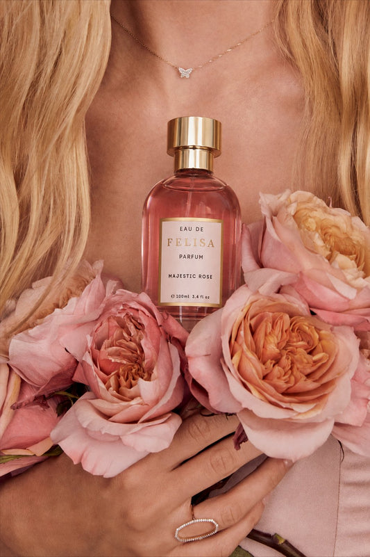 Frasco de Majestic Rose entre rosas, representando a origem afetiva e autoral da Casa FELISA.