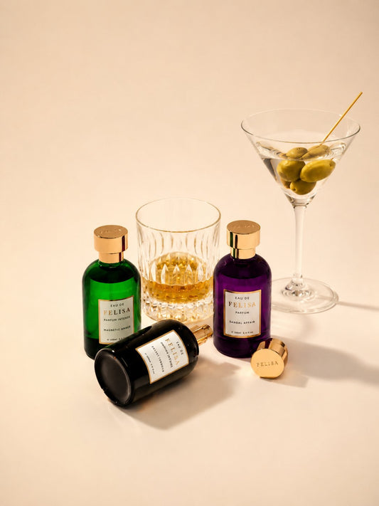Still life com drinks: os perfumes Magnetic Amber, Sandal Affair e Velvet Tobacco da Felisa Beauty ao lado de um copo de whisky e uma taça de martini com azeitonas