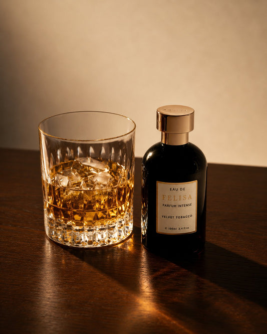 Still de vida com drinks ambientando o perfume Velvet Tobacco da Felisa Beauty, evocando as camadas de cacau amargo, couro e fumaça da fragrância