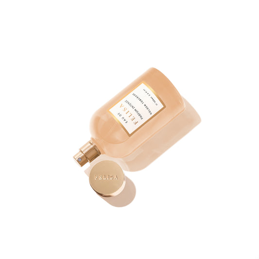 Frasco de Golden Tuberose Intense deitado em fundo claro, com tampa dourada ao lado