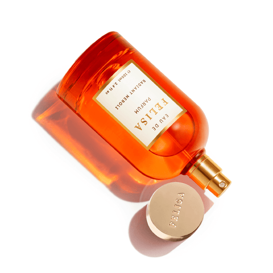 Frasco Radiant Neroli 100ml Eau de Parfum Felisa aberto, tampa dourada ao lado, sobre fundo branco